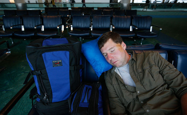 A person using the Pocket Travel Pillow at an airport.